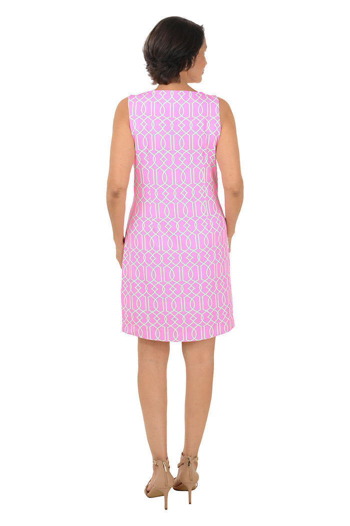 Woman wearing a pink patterned dress on a white background. Back shot.