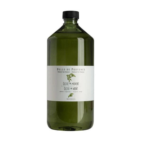A bottle of Belle De Provence liquid soap on a table, with a label that reads 'Olive & Mint'.