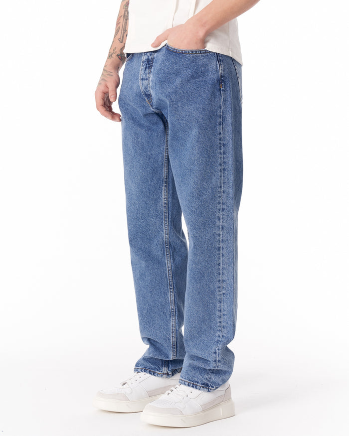 Martin Valen blue loose-fit men's jeans, side mid-body view with hand in pocket and visible center seam