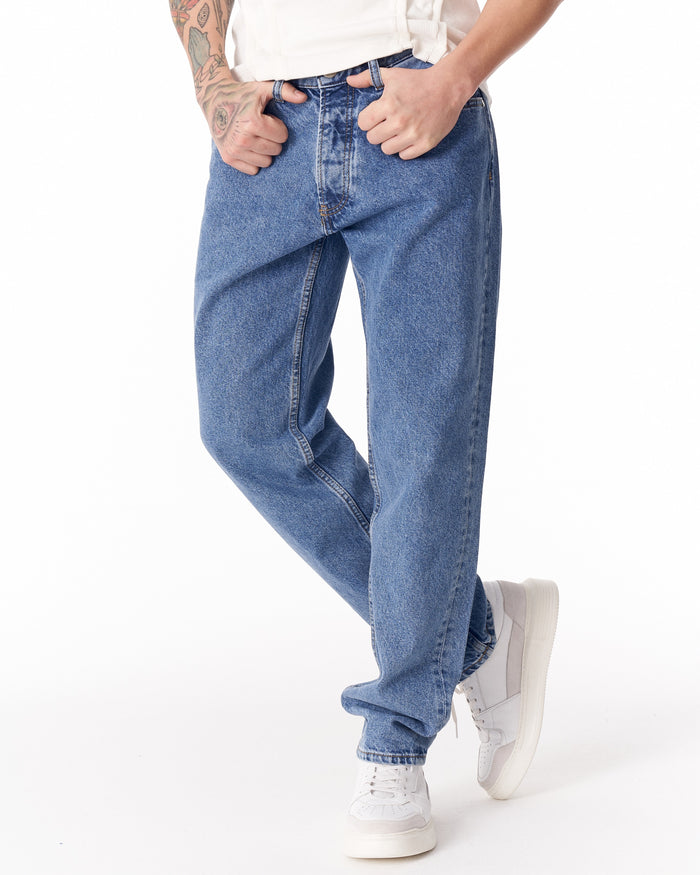 Martin Valen blue loose-fit men's jeans, front close-up with hands in pockets and visible center seam