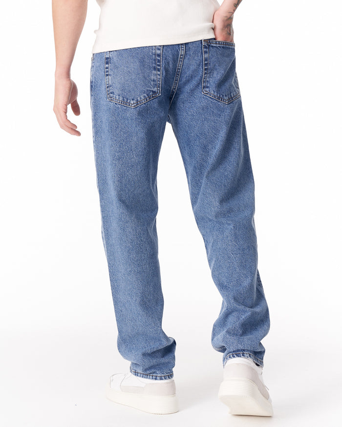 Martin Valen blue loose-fit jeans, three-quarter rear view showing back pockets and white sneakers