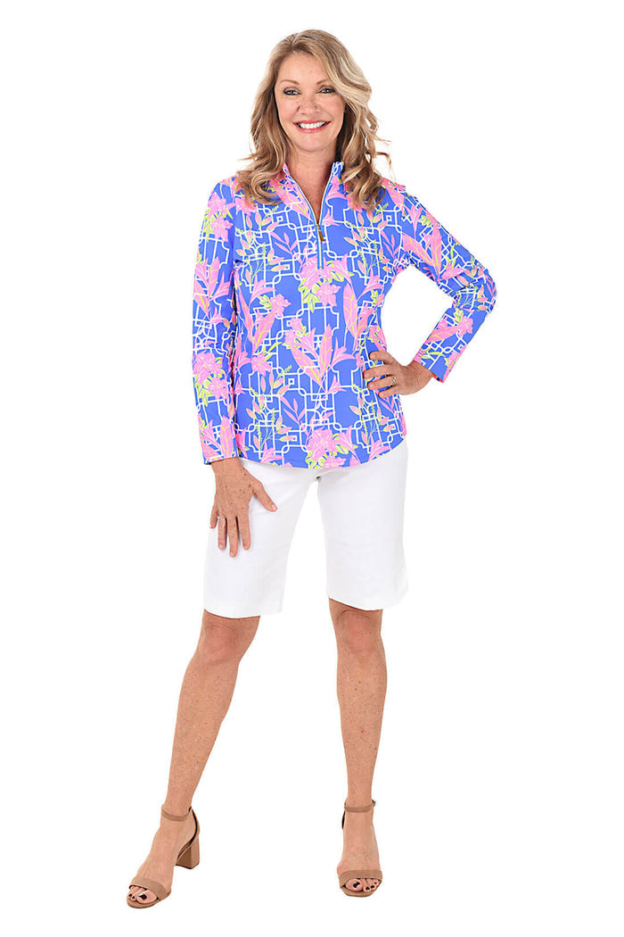 Woman wearing a colorful patterned blouse and white shorts on a white background