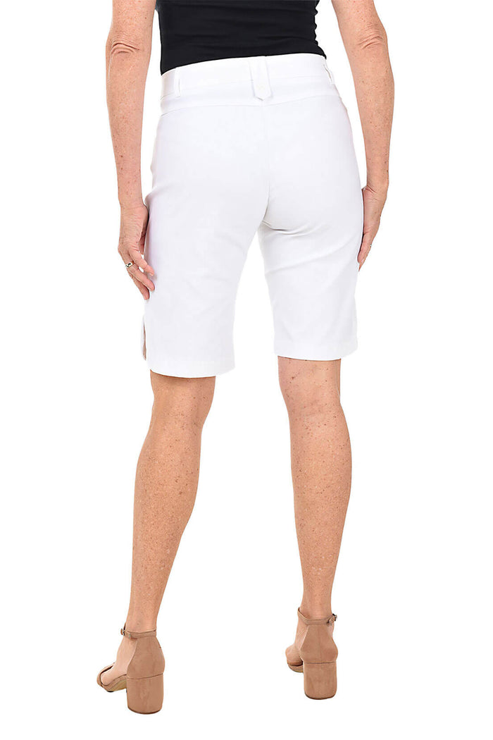 Person wearing white Bermuda shorts on a plain background