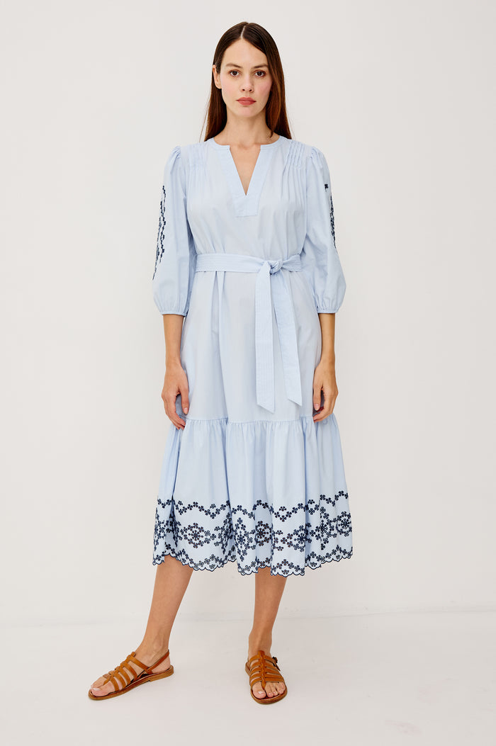 Carmel Peasant Maxi Dress in Poplin With Pleated Shoulders, V-Neckline, Three-Quarter Puff Sleeves, Adjustable Waist Ties, Side Pockets, Tiered Seam, and Contrast Embroidery at Cuffs and Hem in Blue Bird Colorway - Full Body Front View Featured on Model