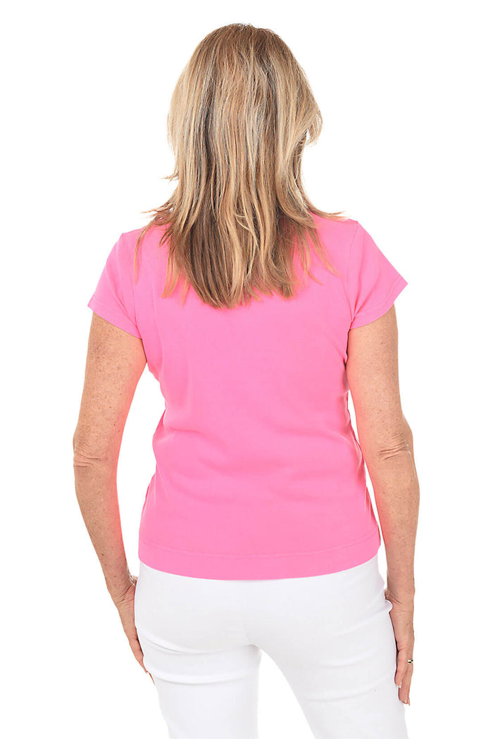 Woman wearing a bright pink shirt with a white background. Back shot