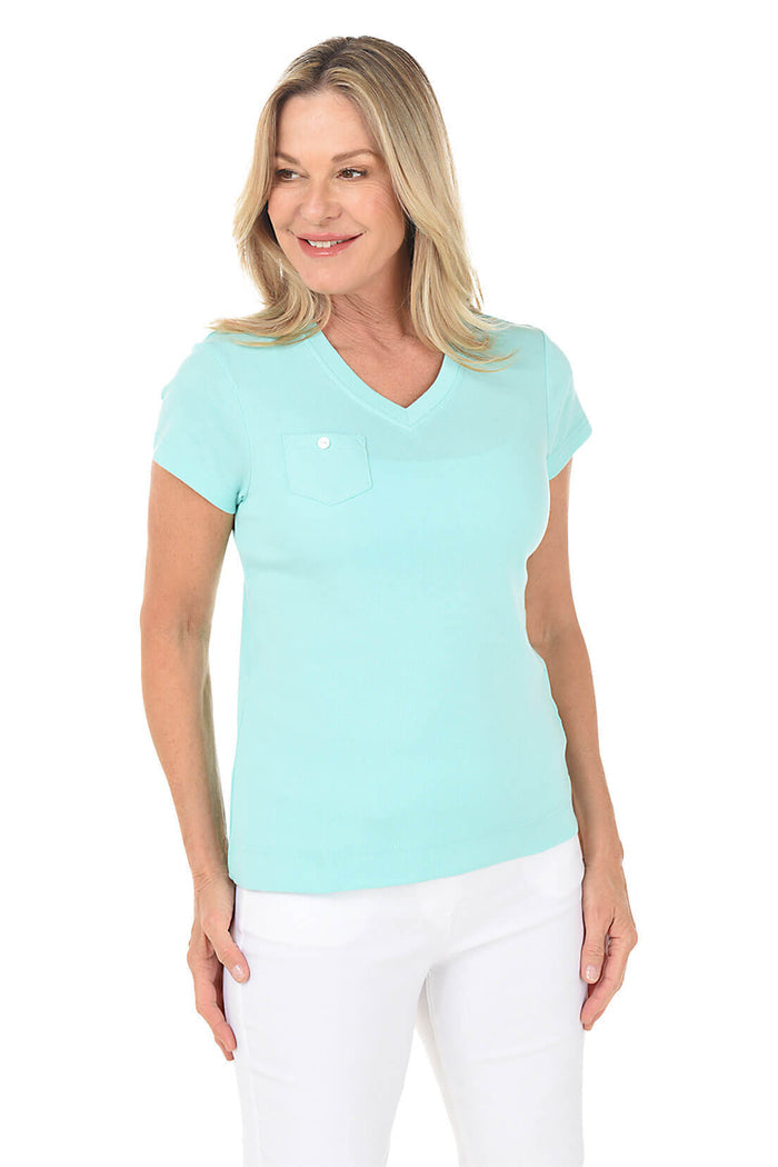 Woman wearing a seafoam blue top and white pants on a white background