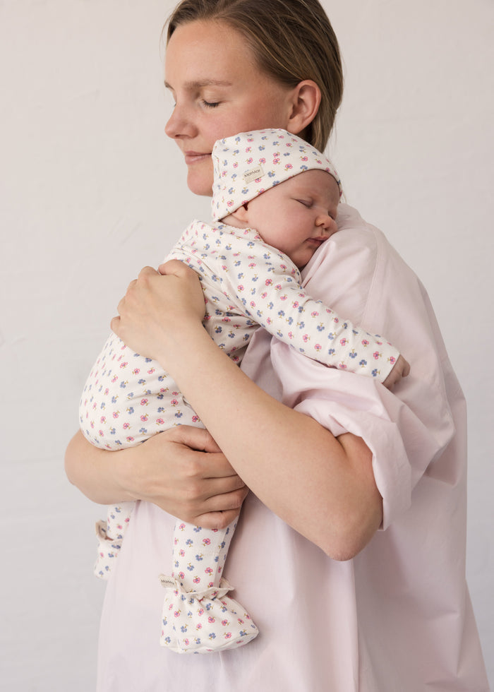 Woman wearing a bright red dress while holding a baby in her arms.