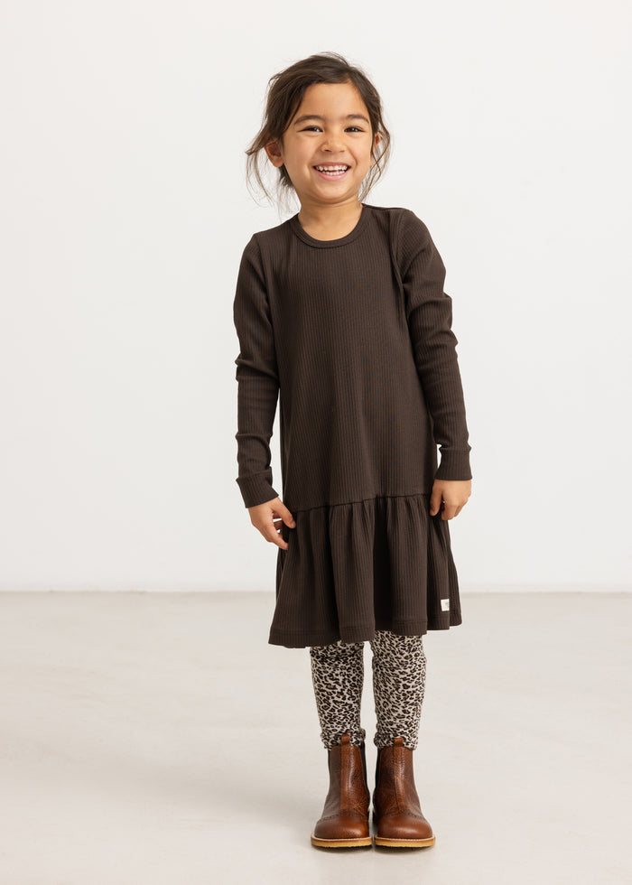 Girl dress in dark brown with long sleeves and a pleated skirt on the model.