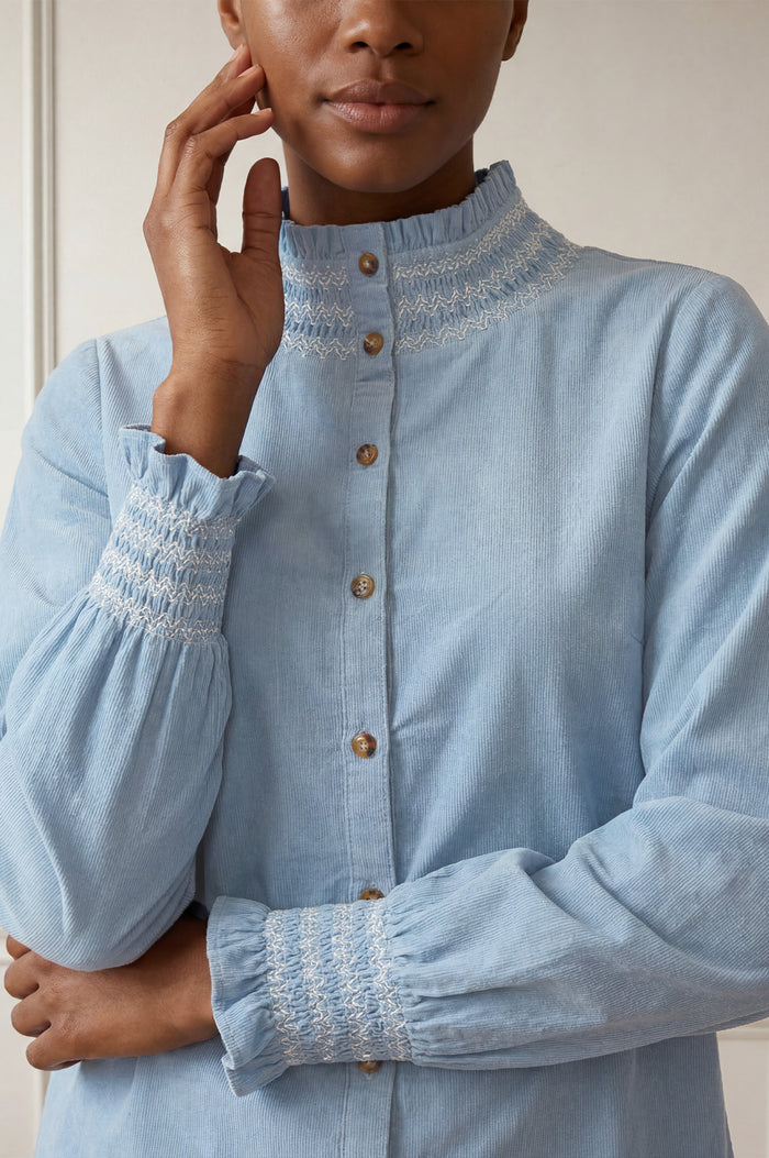 Close-up of the smocked embroidered collar and cuff detail of the Aspiga Embroidered Smocked Baby Cord Blouse in Ice Blue