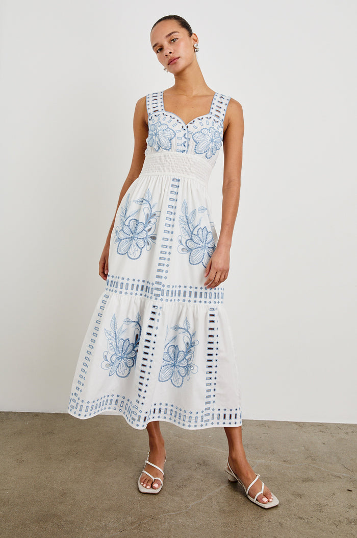 Front view of model wearing our sleeveless, Fawn Midi Dress in White with Blue Embroidery contrast and eyelet details.
