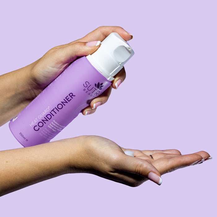 Hand holding a lavender bottle of Heat Guard Conditioner | SUTRA dispensed on the palm against a light purple background, showcasing skincare and hair care product application.