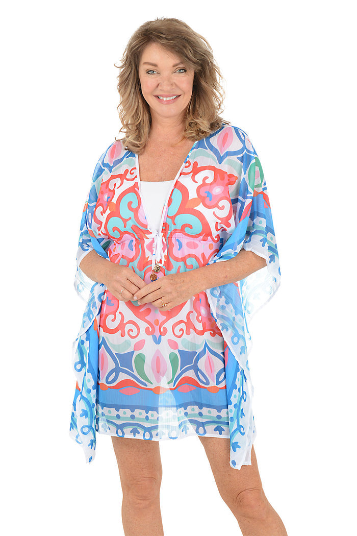 A woman wearing a multi-colored caftan over a white swimsuit.