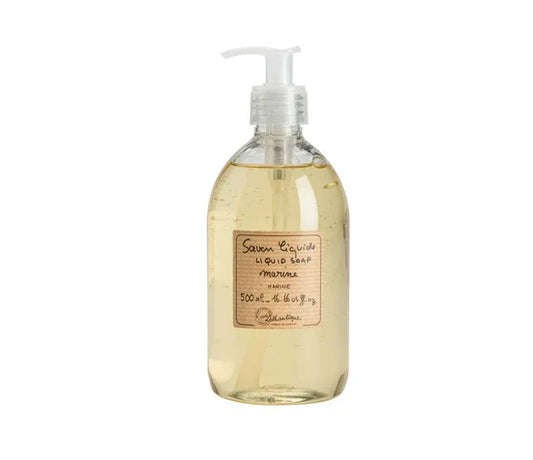 A clear plastic bottle with a white pump dispenser containing liquid soap, placed on a wooden surface.