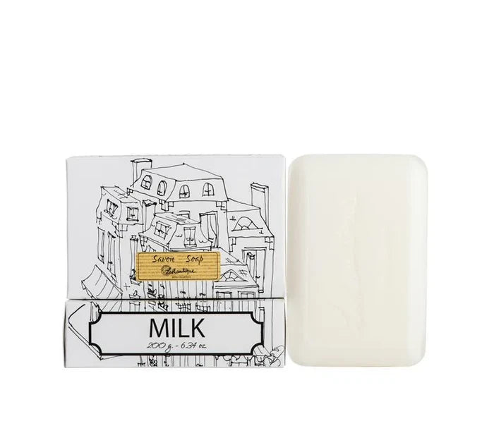A white box of Lothantique bar soap with a drawing of a cityscape and labelled with the scent Milk, beside a white bar of soap.