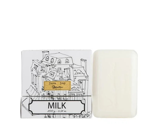 A white box of Lothantique bar soap with a drawing of a cityscape and labelled with the scent Milk, beside a white bar of soap.