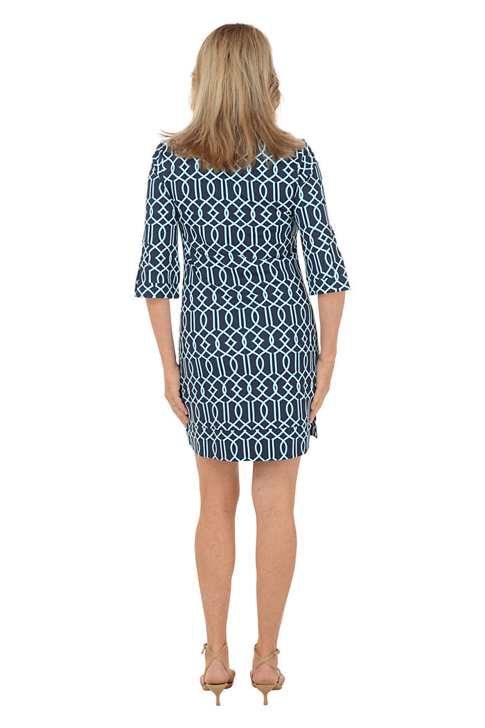 Woman wearing a blue patterned dress on a white background. Back shot.