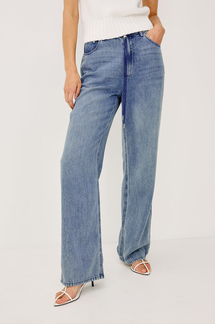 Normandie Pant in Cotton Lyocell Denim With Low-Slung Fit, Adjustable Toggle Drawstring Waist Ties, 5-Pockets, and Loose Fit in Antique Blue Colorway - lower Body Front View Featured on Model