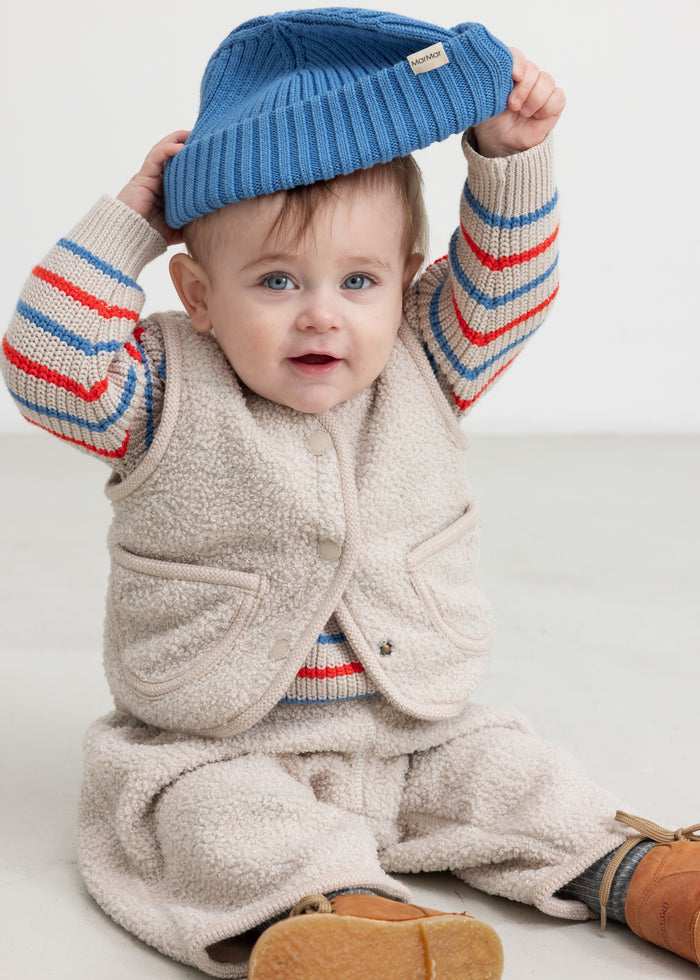 Beige teddy-vest med knapper og lommer, set på barn i løstsiddende model