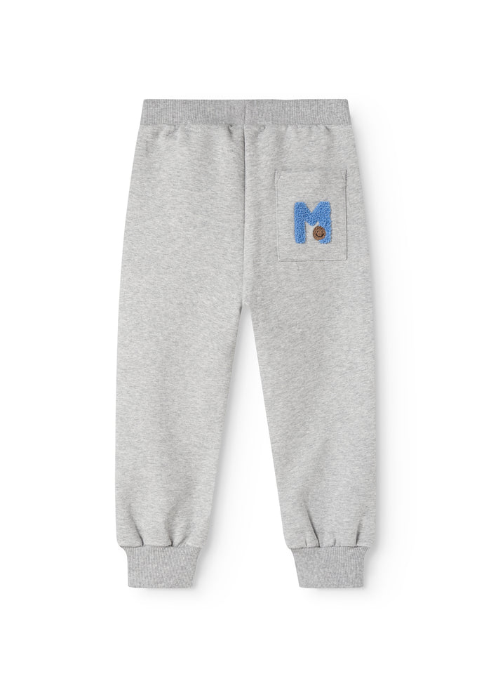 Gray jogger pants for children with a blue logo on the thigh and ribbing at the ankles.