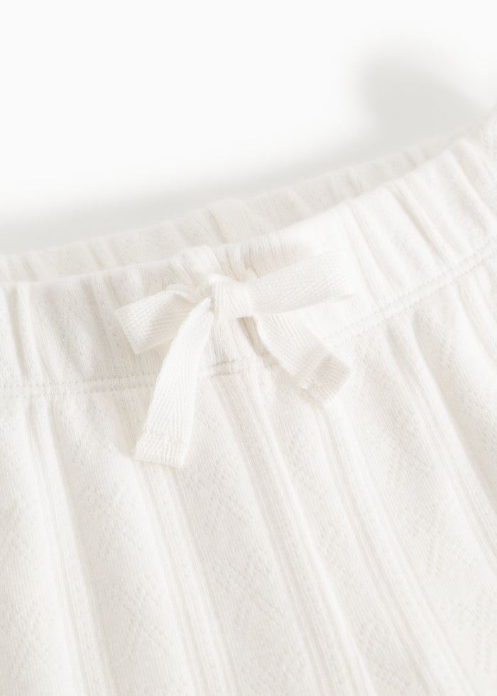 White baby pants from Pitti: elastic waistband with white ribbon bow and texture.