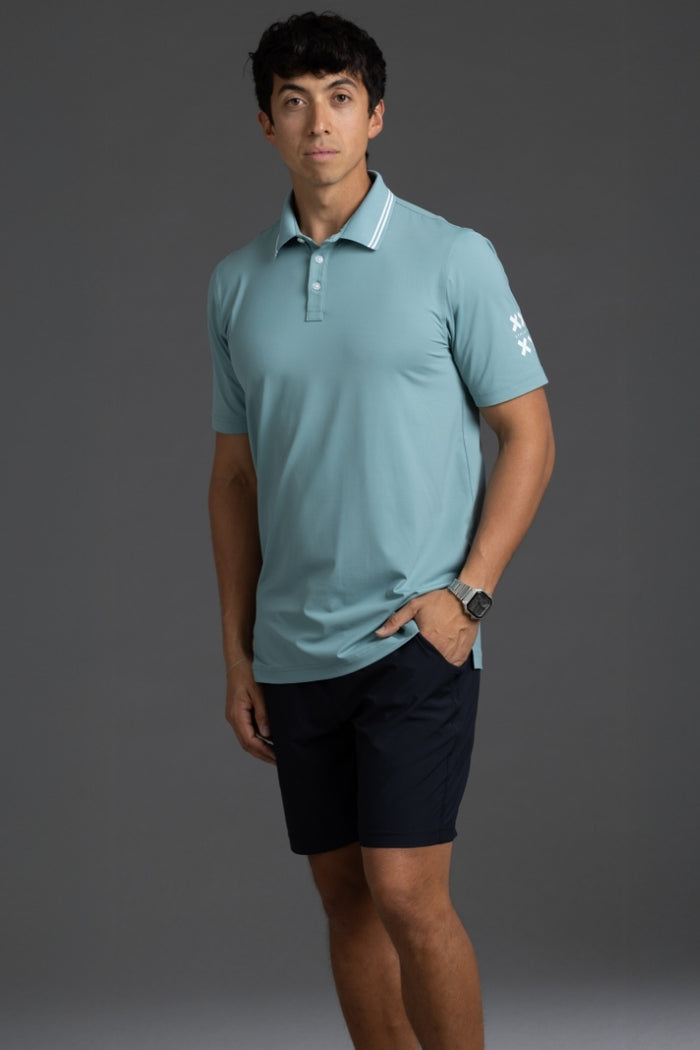 Man wearing a light blue polo shirt and dark shorts against a gray background || Underseas