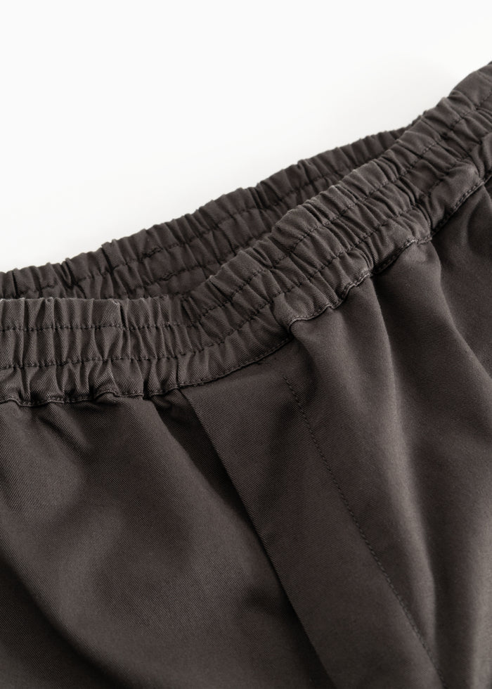 Dark trousers with elastic waistband and seams, detail at the waist.