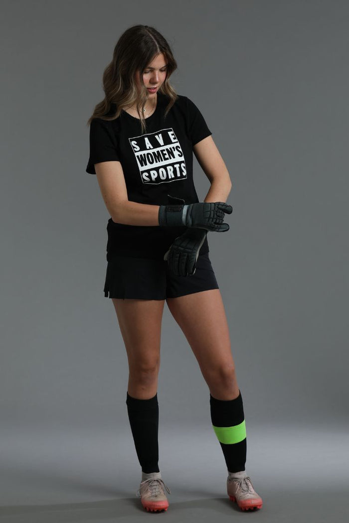 Person wearing a black t-shirt with 'Save Women's Sports' text, black shorts, and knee-high socks with green accents || Black