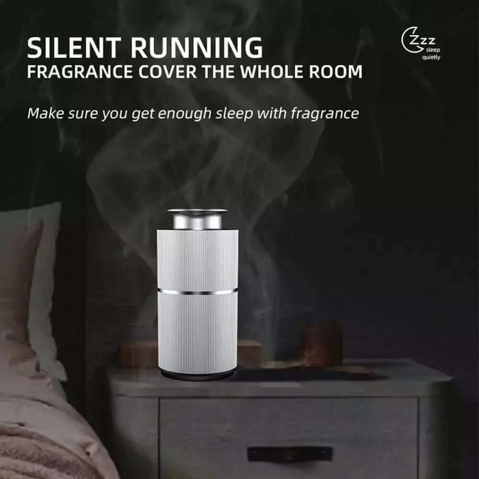 A Smart Mini Scent Diffuser in Rose Gold from ASCENT COLLECTION sits on a bedside table, emitting mist. A bed with a gray wall is in the background. Text reads: This silent running portable diffuser fills your room with luxurious aroma, promoting restful sleep with essential oils.