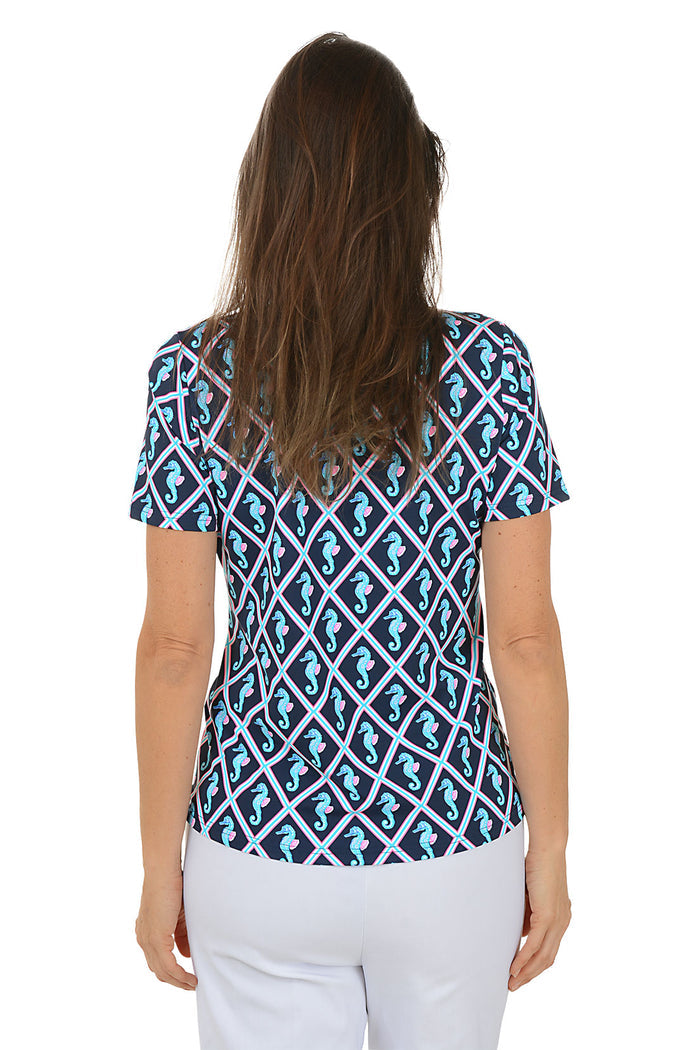 Woman wearing a blue and white patterned top with seahorses on a white background. Back shot.