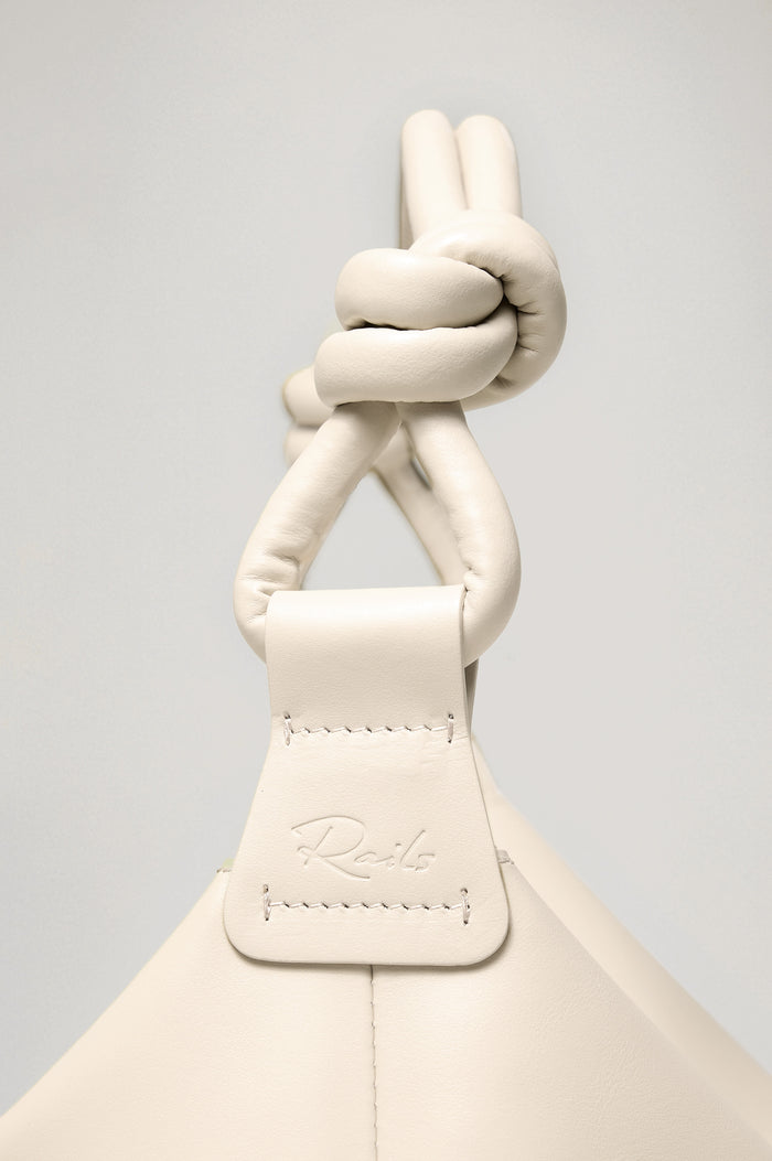 Siena Slouchy Hobo Bag in Italian Leather With Knotted Top Strap, Zipper Closure With Fringe Tassel And Interior Snap Button Slip Pocket in Bone Colorway - Close Up Side View Branded Detail Featured