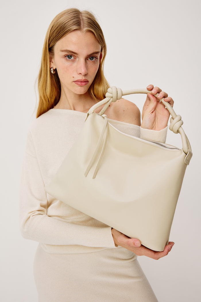 Siena Slouchy Hobo Bag in Italian Leather With Knotted Top Strap, Zipper Closure With Fringe Tassel And Interior Snap Button Slip Pocket in Bone Colorway - Stylized on Model Featured