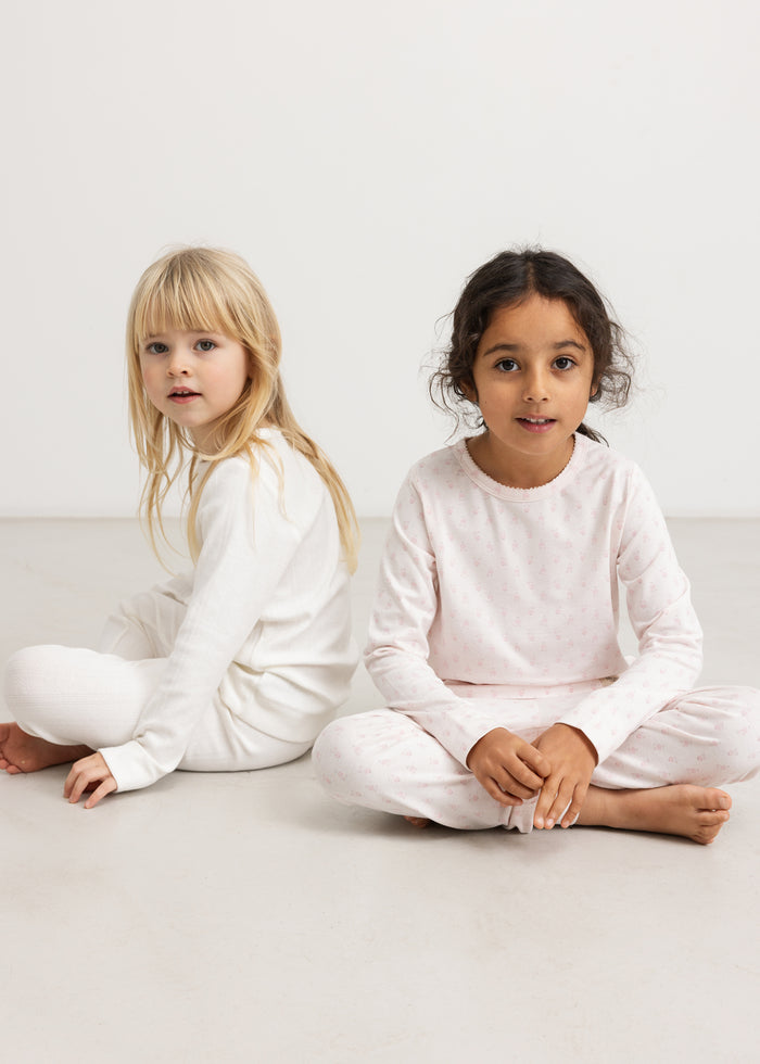 Two children in bright pajamas with a mini floral pattern, long sleeves and pants.