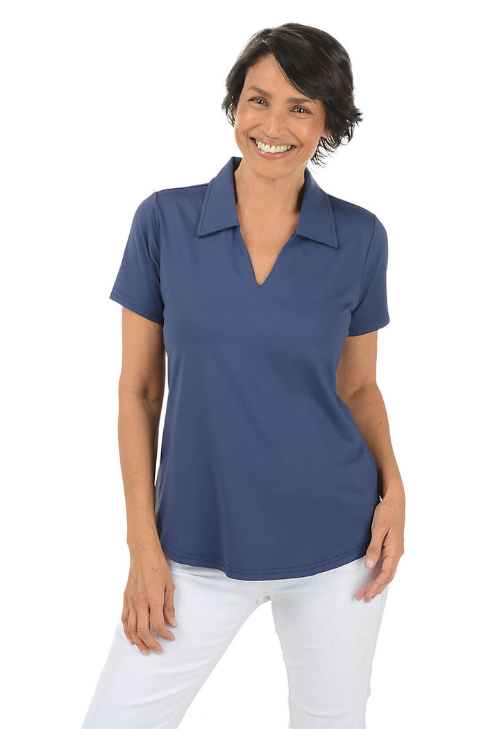Woman wearing a blue polo shirt and white pants on a white background.
