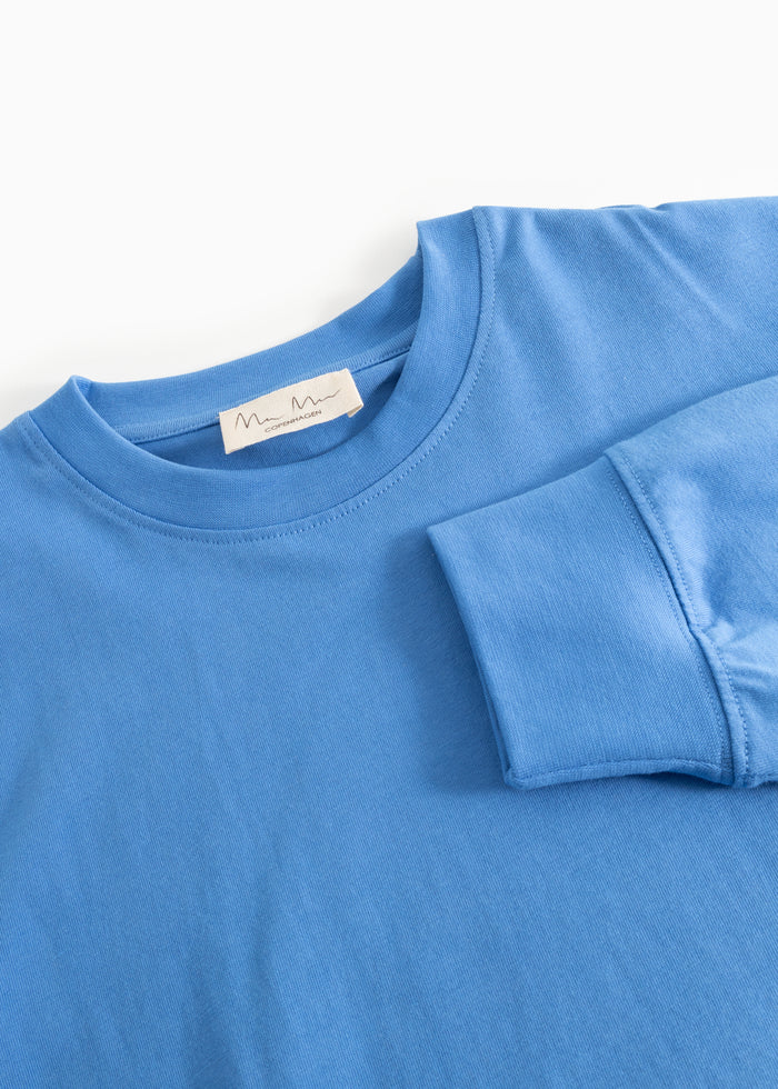 Blue blouse with round neckline and label at the neck.