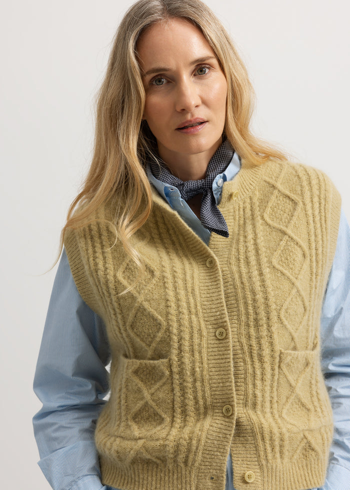 Lightweight knitted sleeveless vest with a check pattern and buttons, over a blue shirt.