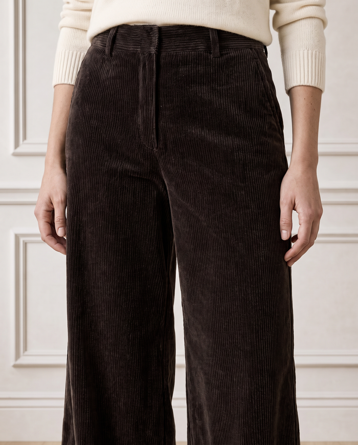 Close-up crop of a model wearing the Aspiga Wide Leg Chunky Corduroy Trouser in Chocolate Brown with a cream jumper, front view