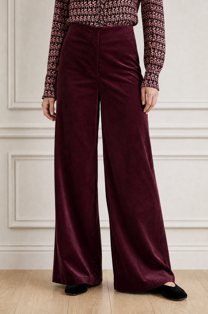 Model wearing the Aspiga Wide Leg Stretch Corduroy Trouser in Burgundy, a high-waisted wide-leg velvet corduroy trouser, front view