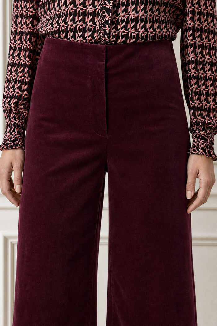 Model wearing the Aspiga Wide Leg Stretch Corduroy Trouser in Burgundy, a high-waisted wide-leg velvet corduroy trouser, alternate view