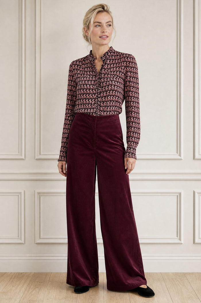 Model wearing the Aspiga Wide Leg Stretch Corduroy Trouser in Burgundy, a high-waisted wide-leg velvet corduroy trouser, alternate view