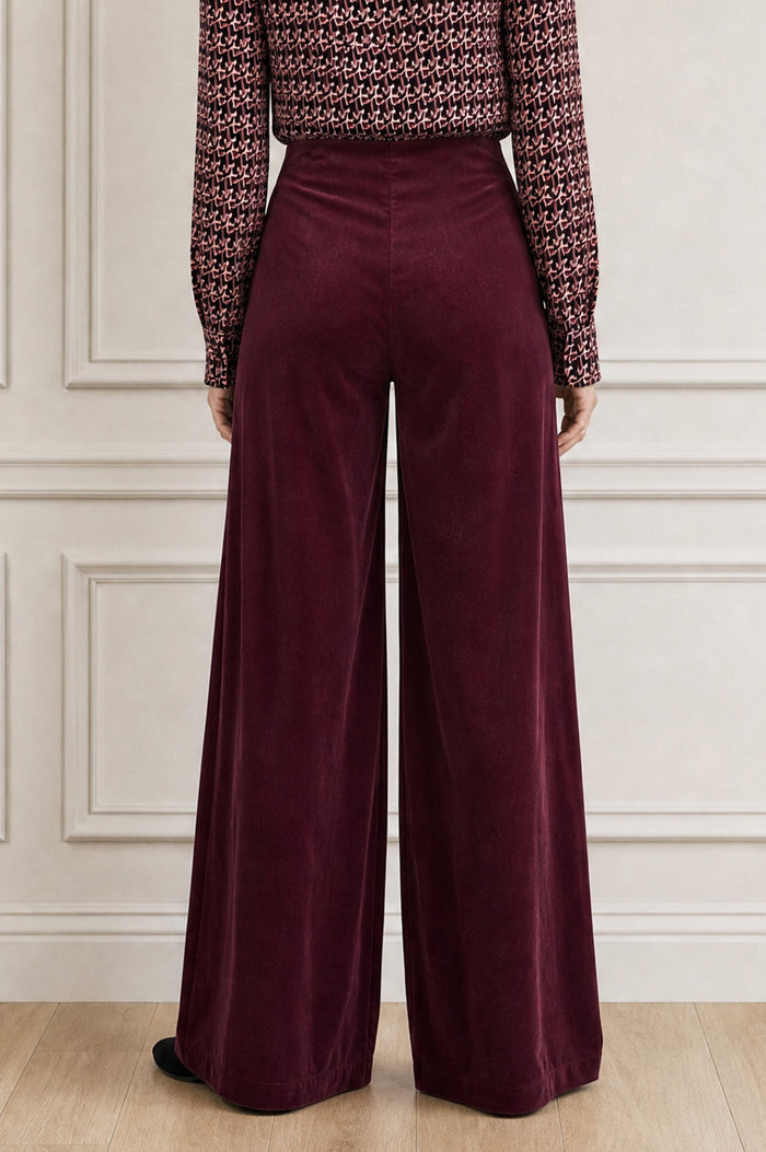 Additional styled photo of a model wearing the Aspiga Wide Leg Stretch Corduroy Trouser in Burgundy, a high-waisted wide-leg velvet corduroy trouser