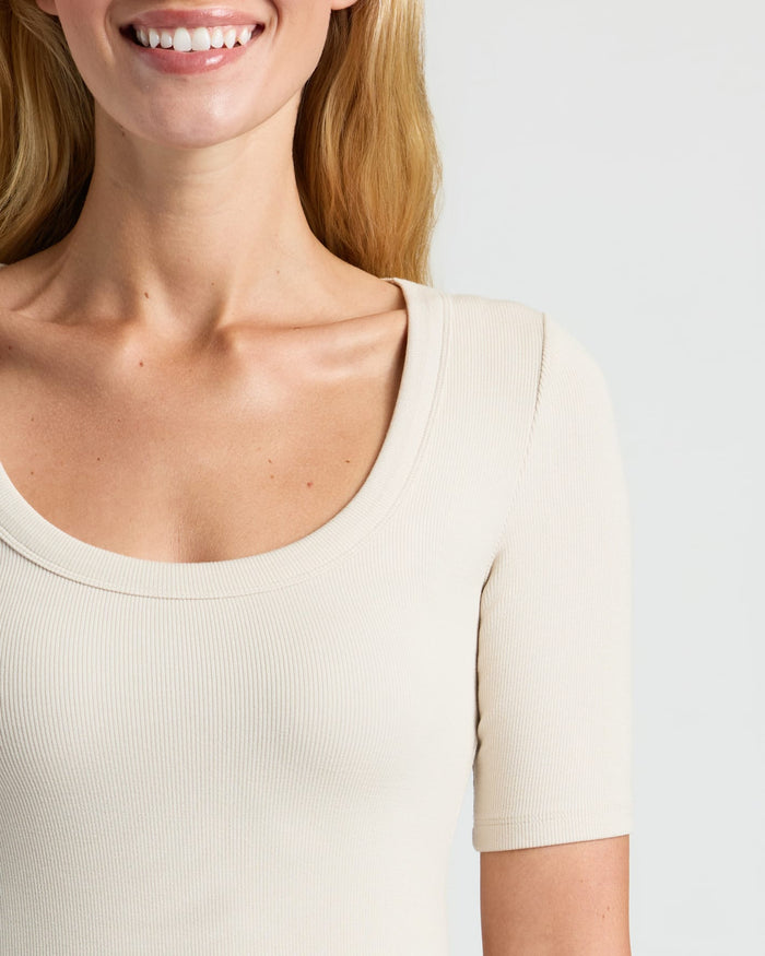 Woman wearing cream ribbed tee, showcasing Women's Ribbed 3/4 Sleeve Scoop Neck Tee.